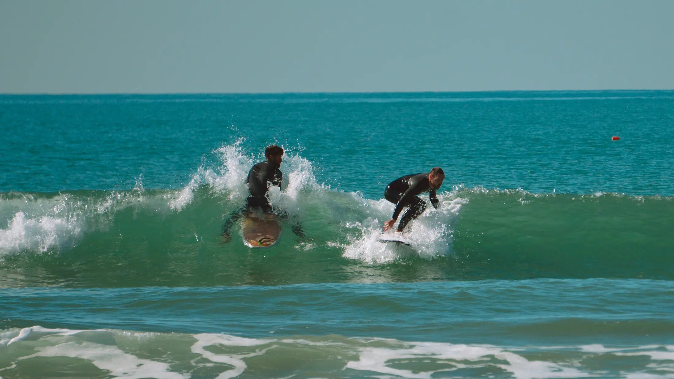 Brahim sharing a small wave with another surfer